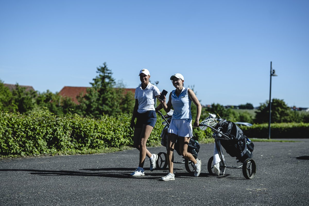 Zwei Spielerinnen mit Trolleys auf dem Weg zum Platz
