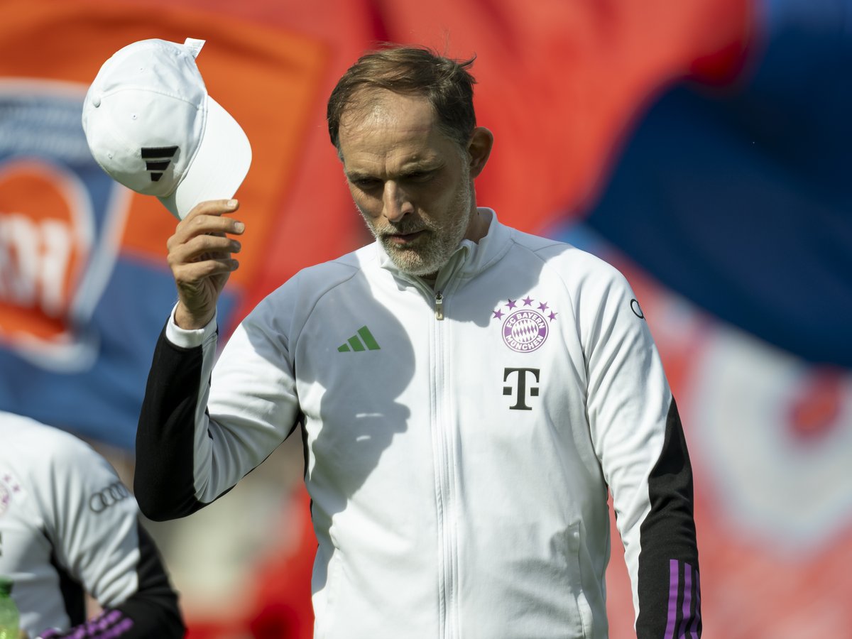 Thomas Tuchel, Trainer des FC Bayern München, zieht vor rot-blauen Fahnen die Kappe