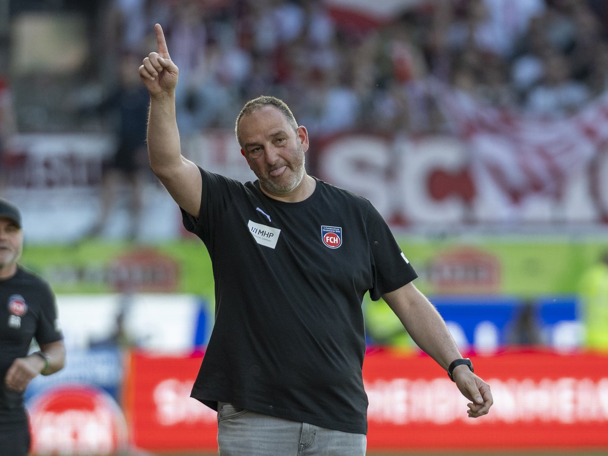 Frank Schmidt zeigt mit erhobenem Finger zur Tribüne